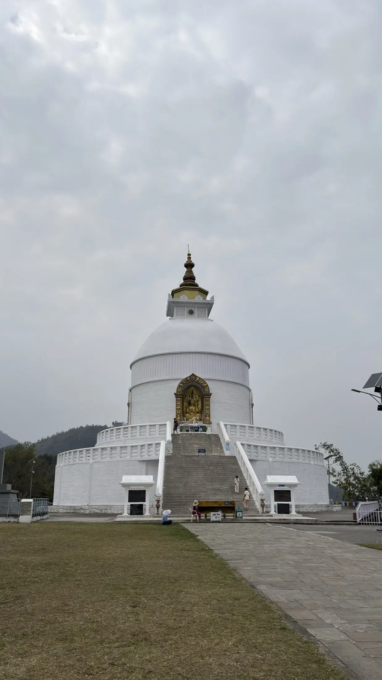 The white World Peace Pagoda in Pokhara beneath an overcast sky