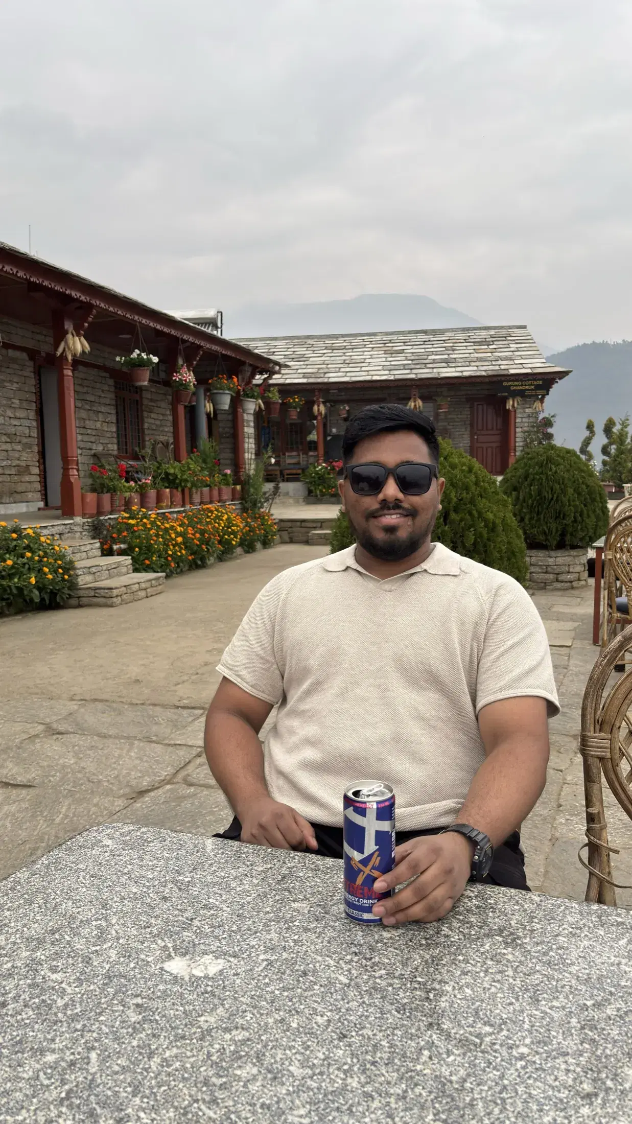 Manish seated in the flower-filled courtyard of Gurung Cottage in Ghandruk