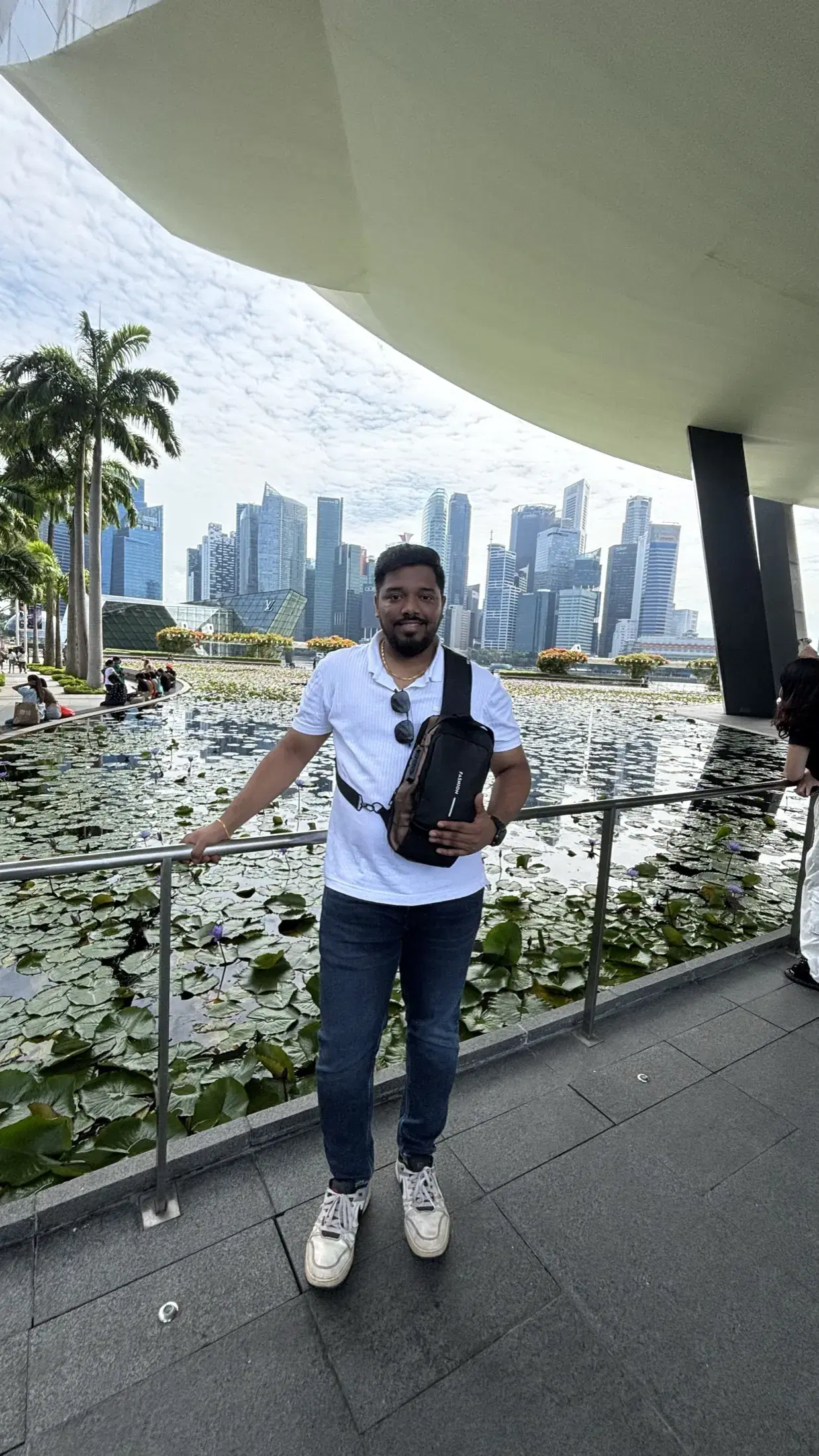 Manish beside the lotus pond at the ArtScience Museum with the downtown skyline behind him