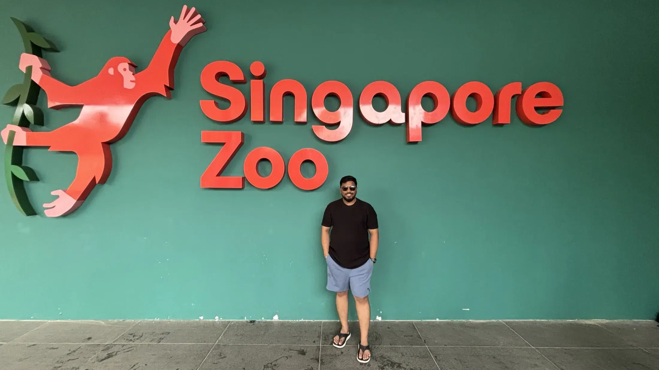 Manish standing beneath the large Singapore Zoo wordmark