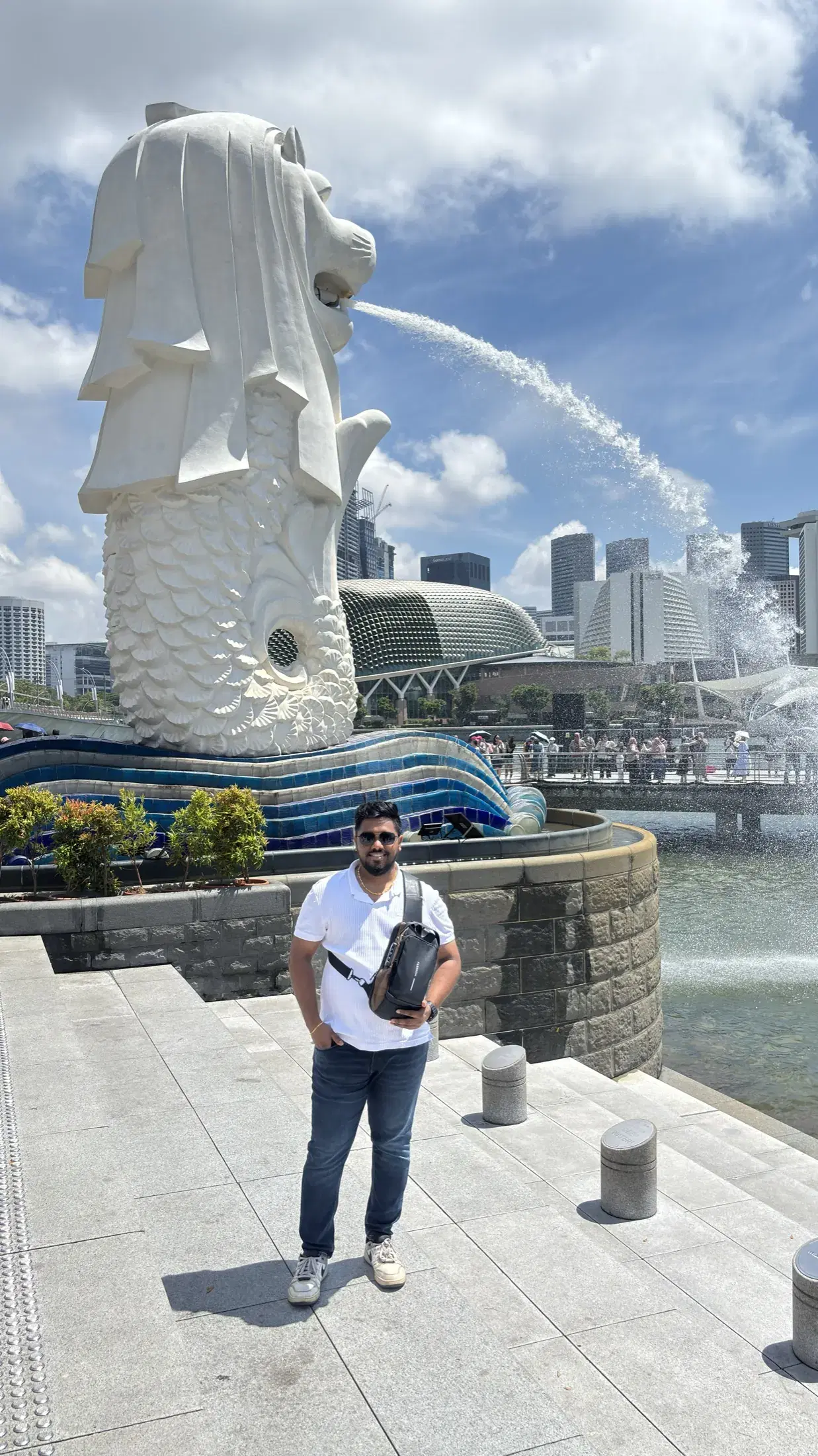 Manish standing close to the Merlion fountain under a bright blue sky