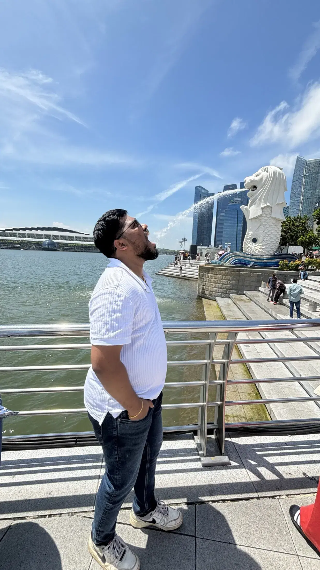 Manish posing in perspective with the Merlion's water stream at Marina Bay