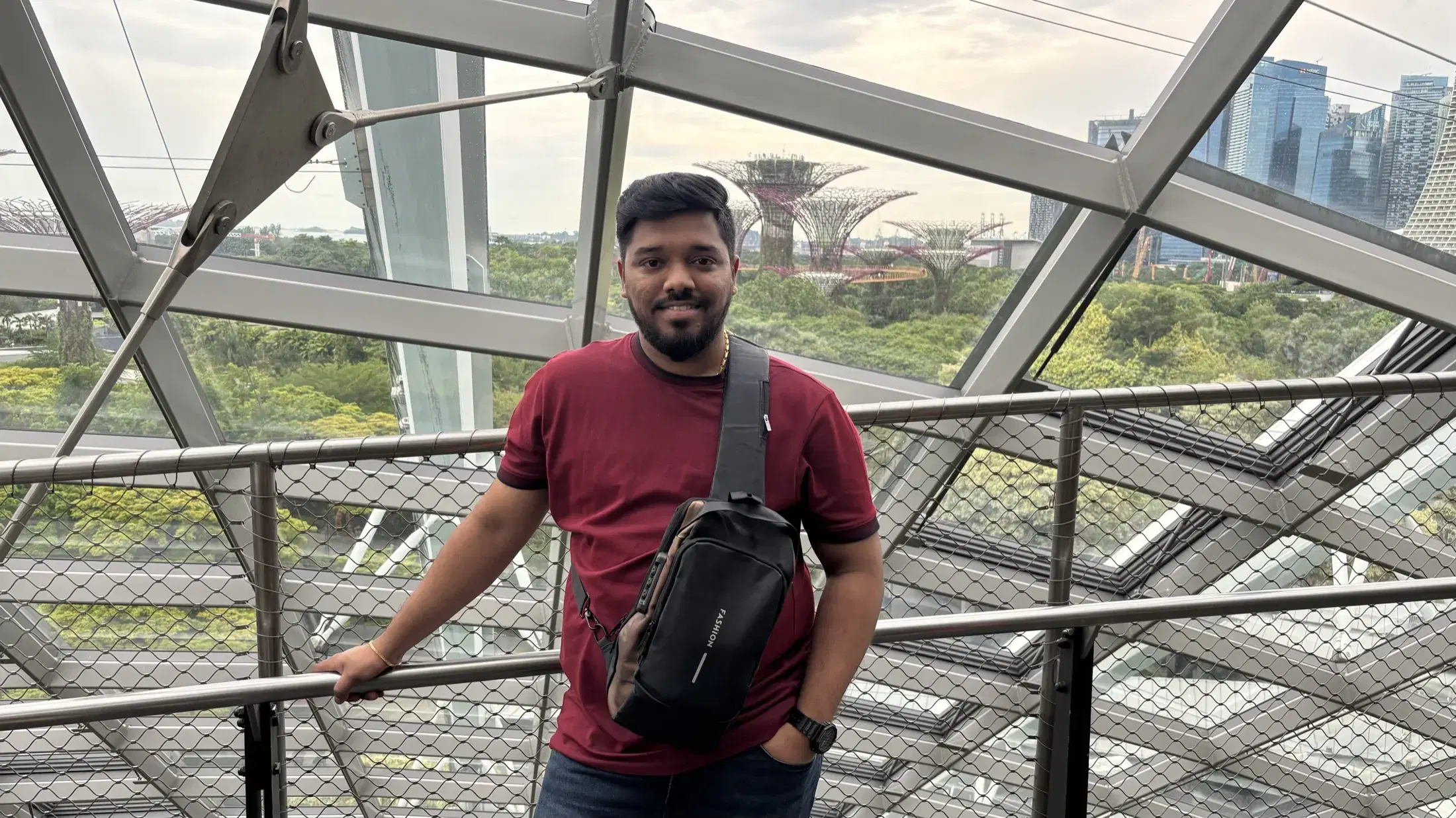 Manish inside a glass conservatory with the Supertree Grove visible behind him
